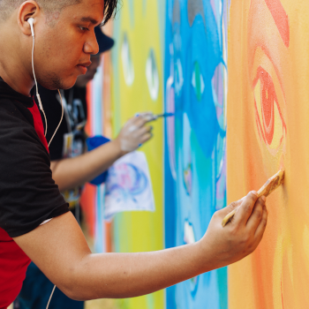 Young man painting a colorful mural
